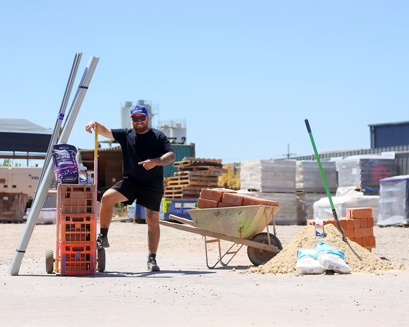 The compact Nexbrick install kit beside the wheelbarrows, sand and pallets of a traditional masonry setup